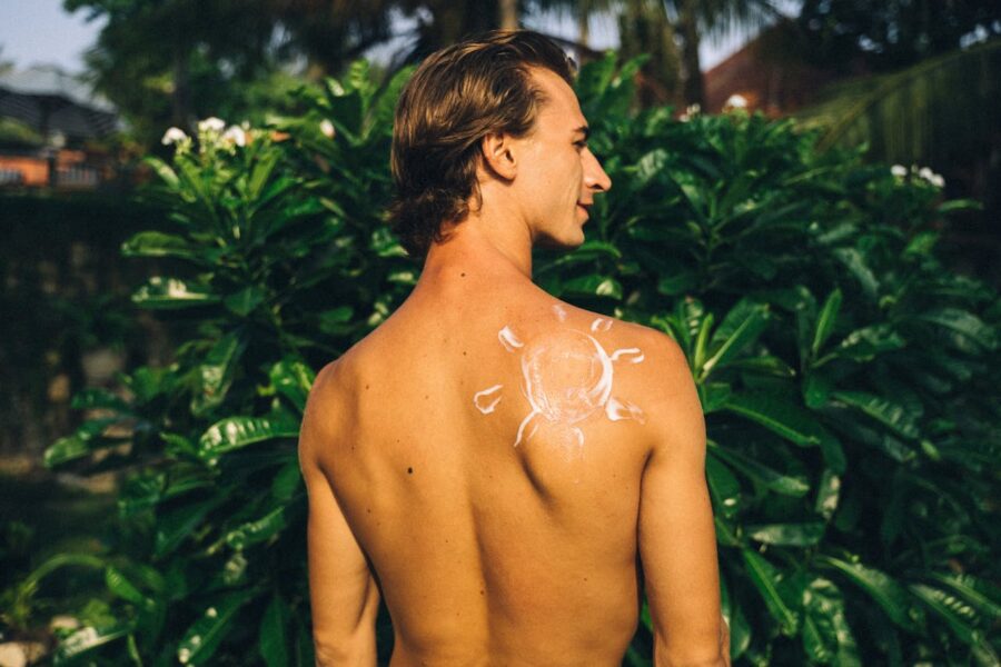 sun cream applied to a males back in the shape of the sun